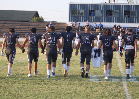 Senior football players escort the jersey of Creed Bouse