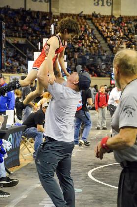 Coach Dickerson lifts Hunter Larsen proudly into the air after his win. Photo by Erin Dudgeon.