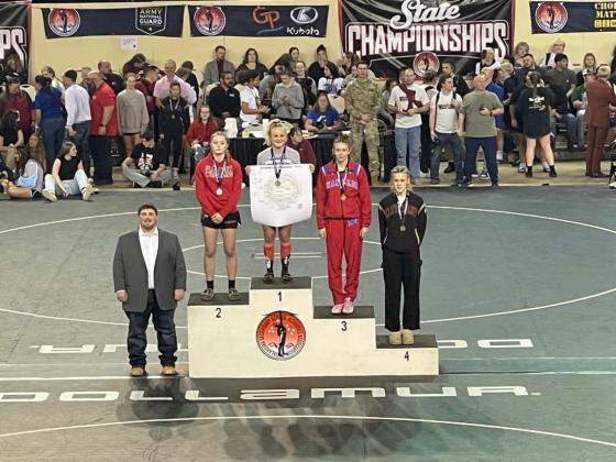 A proud coach Jacolby Mitchell stands next to the podium as Baylor Moore secures the top spot - Contributed Photo