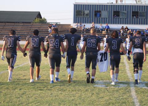 Senior football players escort the jersey of Creed Bouse