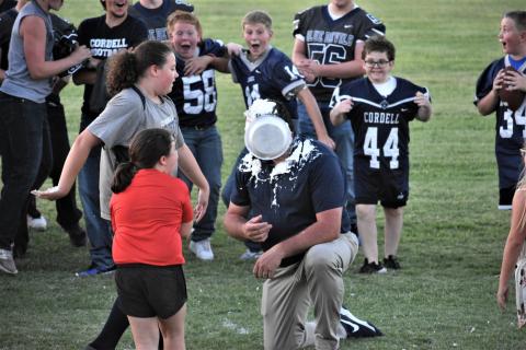 Emma Holman puts a pie to the face of her dad, Assistant Football Coach Buddy Holman, as her sister Ellison Holman watches. Photo courtesy of Charlinda Ogle