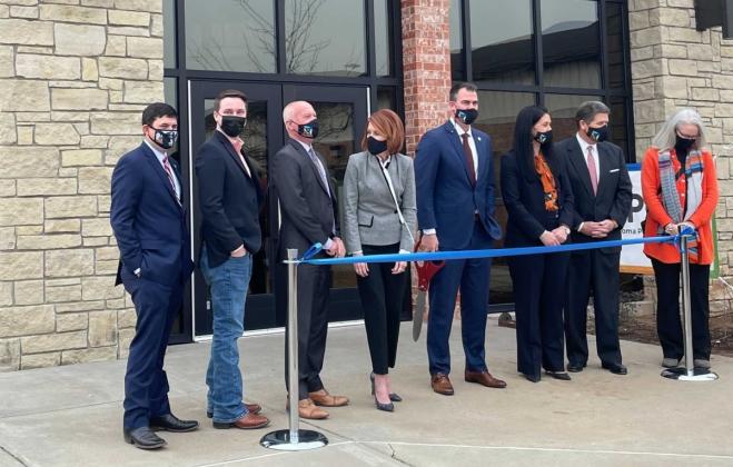 Oklahoma Gov. Kevin Stitt, center holding scissors, and state cabinet secretaries pose during a Jan. 21 ribbon-cutting ceremony at the newly relocated state Public Health Lab in Stillwater. (Oklahoma State Department of Health)