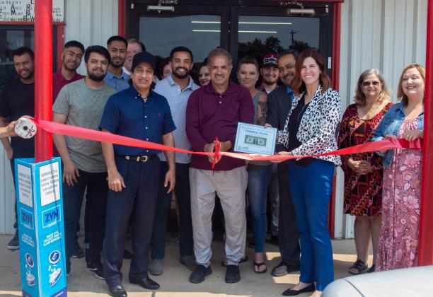 Store owners and their family members gather together alongside Cordell Chamber of Commerce members as the chamber presents Cordell Plaza with their first dollar during the grand opening event. PHOTO BY HECTOR LUCAS