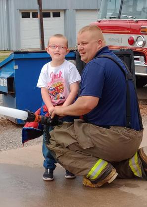 A student gets the chance to use the fire hose thanks to a Cordell fire fighter.PHOTO BY HEATHER FLORES