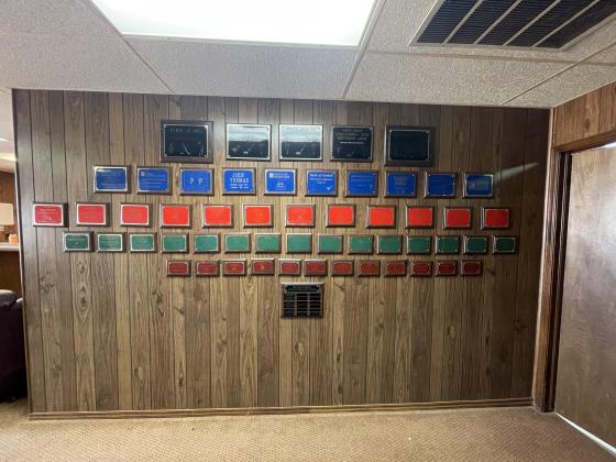 “We had to have this wall right here to be able to build all that out there.” Jerry Burrows emphasized the importance of the many donors whose names are displayed on plaques in the clubhouse. PHOTO BY BROOKLYNN PEEK