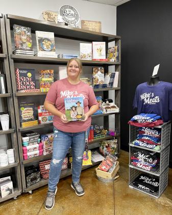 Mike's Meats offers and exceptional variety display of cookbooks, mugs, tumblers, and more. Ryleigh Longs stands with an excellent cookbook choice.