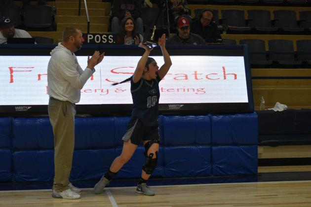 Coach Vaughn Blankenship applauds as McKinsey Gray holds the team trophy high after the Lady Blue Devils defeat the Sweetwater Lady Bulldogs PHOTO BY CHARLINDA OGLE