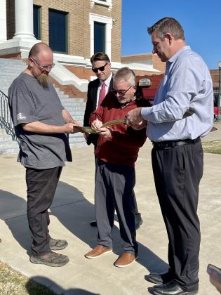 Cordell Mayor Phil Kliewer signs the golden shovel that Dobson Fiber will display in their office as Cordell Chamber of Commerce President Jeremey Goodson and Cordell City Attorney await their turn. Photo by Brooklynn Peek