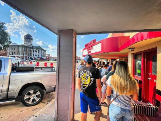 Movie-goers line up along the sidewalk outside the Washita Theatre for Twisters
