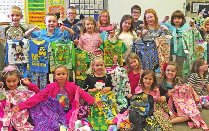 Above: Children pose with pajamas they brought to school for donation. Mrs. Powers says the children get really excited about helping others and selecting pajama sets to donate.