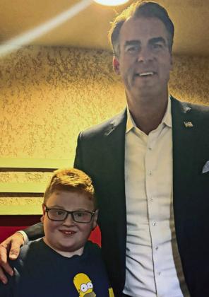 Right: Jaxon Fuller got a special front row seat next to Governor Stitt, who asked him if he wanted to be Governor someday. He said “Yes,and then President!”
