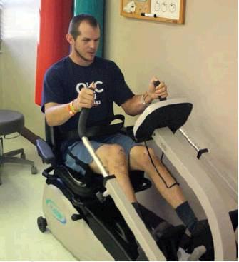 Above: Devin Humphrey exercising his knee during physical therapy following his Aug. 9, 2019, plane crash in Cordell, photo by Bob Henline. Left: Humphrey immediately following his crash, photo courtesy of Devin Humphrey.