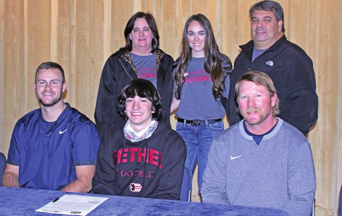 Cordell High School senior Raydon Kuehne, front center, signed to play football at Bethel College in North Newton Kansas. With Kuehne are, front row, Blue Devils head coach Zane Trammell and assistant coach, Dillon Ball. Back row, left to right, mom Nikki Kuehne, sister Kaitlyn and dad Rob. PHOTO BY FLORA WALTERS