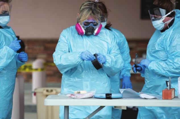 During strong winds, a nurse pulls a piece of tape to help hold down her gown while she works at a Shawnee drive-through site where people are being tested for the coronavirus on April 2. (Whitney Bryen/Oklahoma Watch)