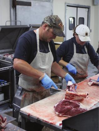 Keith Schneberger, of Keith's Butcher Shop, works alongside one of his employees processing beef in his Burns Flat shop. Bob Henline | The Cordell Beacon