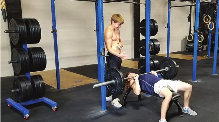 Adden Zanghi spots Dane Corbin while lifting weights at Code Blue gym, which reopened Monday, May 4. Bob Henline | The Cordell Beacon