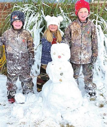 Ransik, Emalyn and Brody Kemp stand next to the snowman they built.