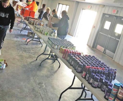 Above: Volunteers pack cases of fruit into individual servings. Right: Non-Perishable food items sit ready in an assembly line. PHOTOS BY CANDY ROGERS