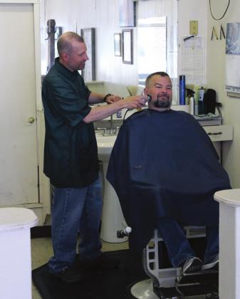 Cordell barber Jud Regier gives Mike Southerland a trim on his first day back in business after being forced to close by COVID-19 restrictions. Bob Henline | The Cordell Beacon