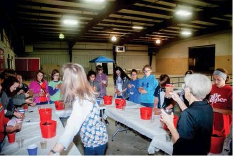Charlene Thornbrough (right), Farm Bureau Women’s Leadership Committee, explains to students about planting seeds as they create their own dirt babies to take home. Photo courtesy of Larry Peck.