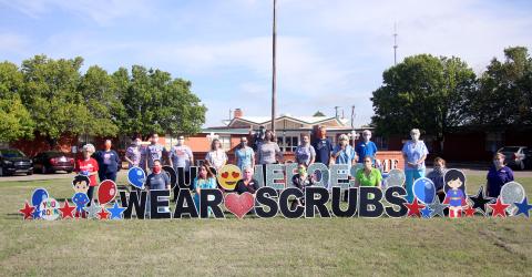 Cordell Christian Home staff gather around a sign celebrating their efforts to keep residents both safe and happy. Bob Henline | The Cordell Beacon