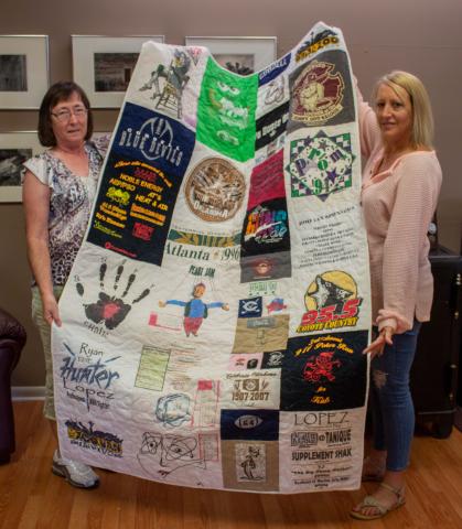 Patricia Mitchell (left) and Charla Ingram (right) hold up the memory quilt that Mitchell created for Ingram.