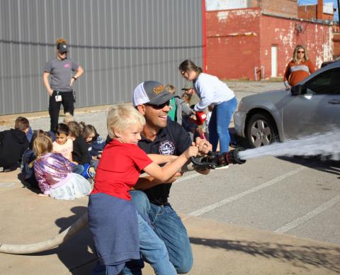 Firefighter Heath Syfert helps Levi Sperle hold the fire hose
