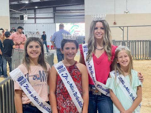 Teen Miss Rylee Kelly, Junior Miss Bailey Gossen, Miss Taylor Sullivan, and Little Miss Kendallyn Gossen carry out their first official duties by presenting prize ribbons at the Washita County Free Fair livestock show. Photo by Patsy Sullivan