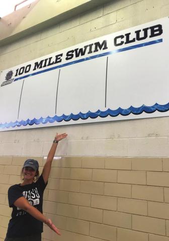 SWOSU graduate student Summer Pennington shows the new wall of fame for the 100- and 200-mile swim clubs at SWOSU.